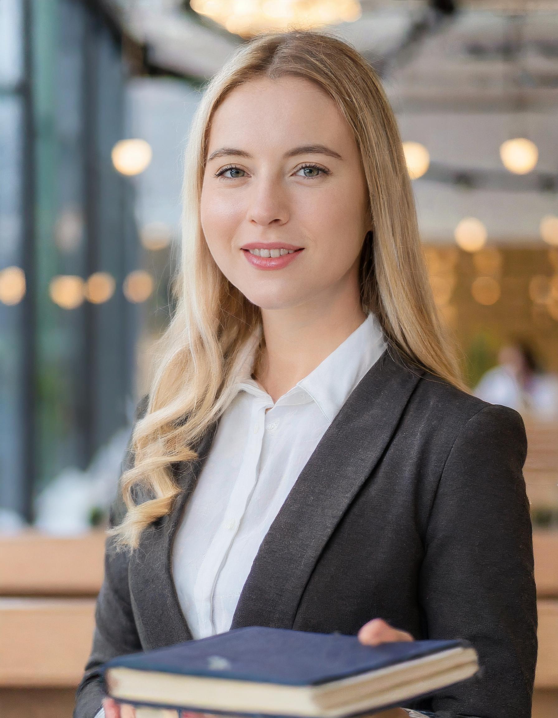 Porträt einer professionellen Frau in formeller Kleidung, die lächelt und selbstbewusst aussieht.